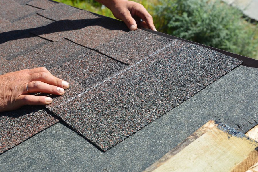 Person installing shingles on residential home