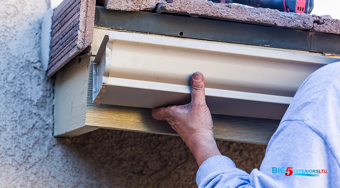 Person measuring and installing gutter on home